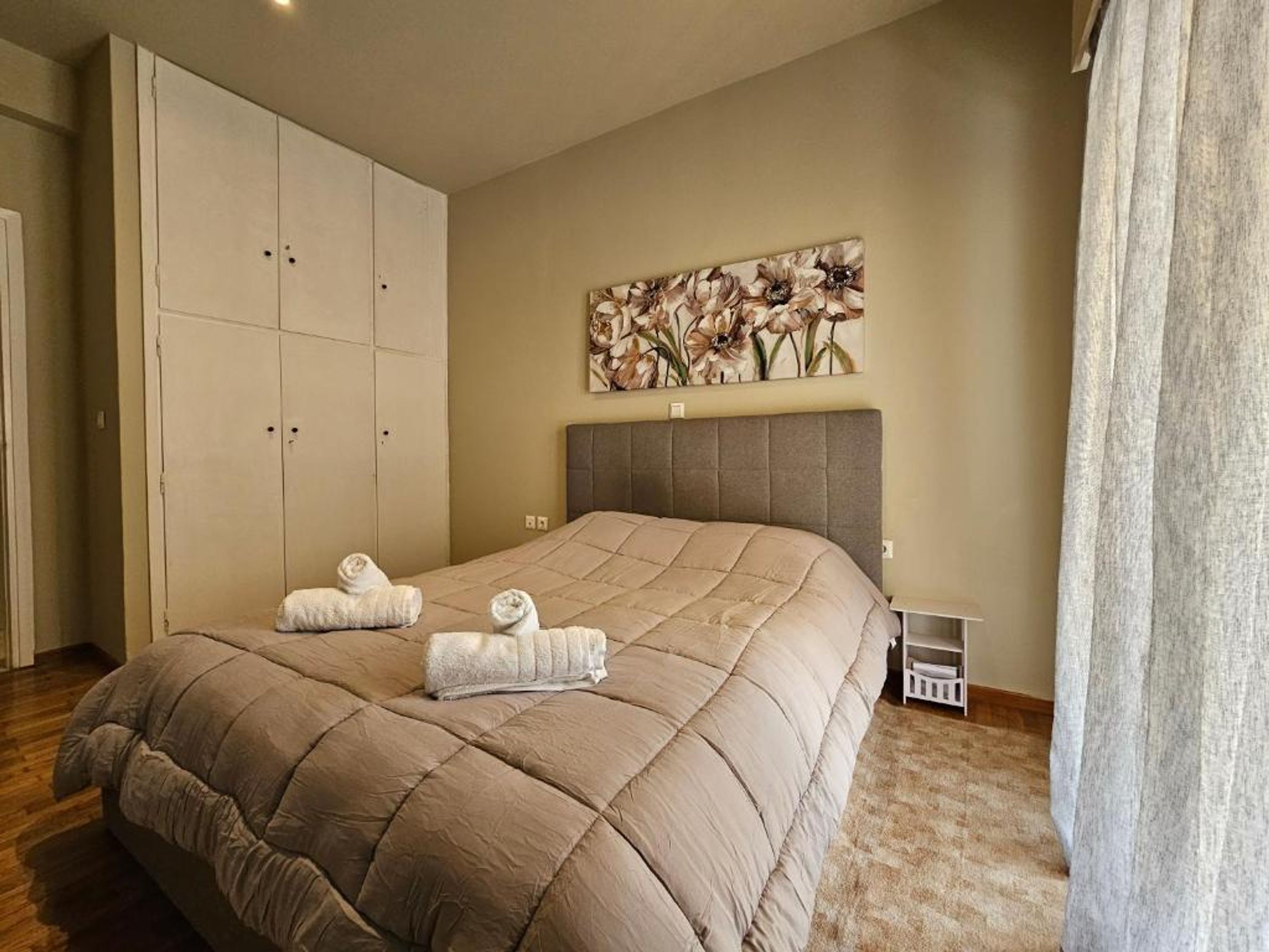 Un dormitorio con una cama grande, un armario, un cabecero y un cuadro en la pared.