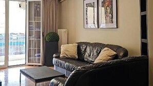 Un salon moderne avec un canapé en cuir noir, une petite table et une grande fenêtre donnant sur un beau paysage.