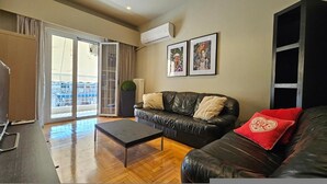 Un salon moderne avec un canapé en cuir, une table basse et une grande porte-fenêtre coulissante donnant sur un balcon.