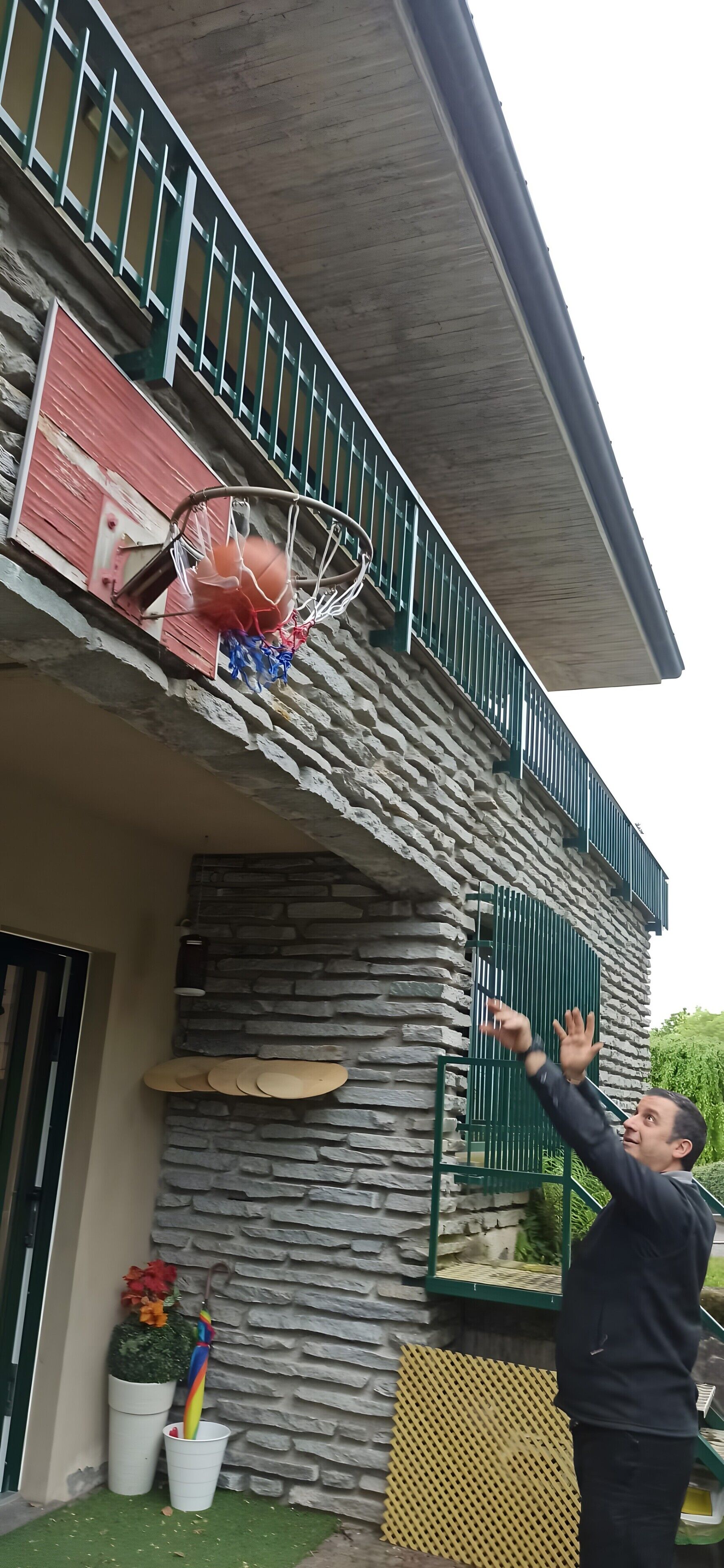 A stone building with a basketball hoop on the balcony.