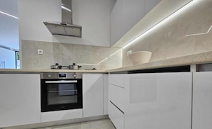 Een moderne keuken met een ingebouwde oven, een roestvrijstalen afzuigkap en een aanrecht met een kom.