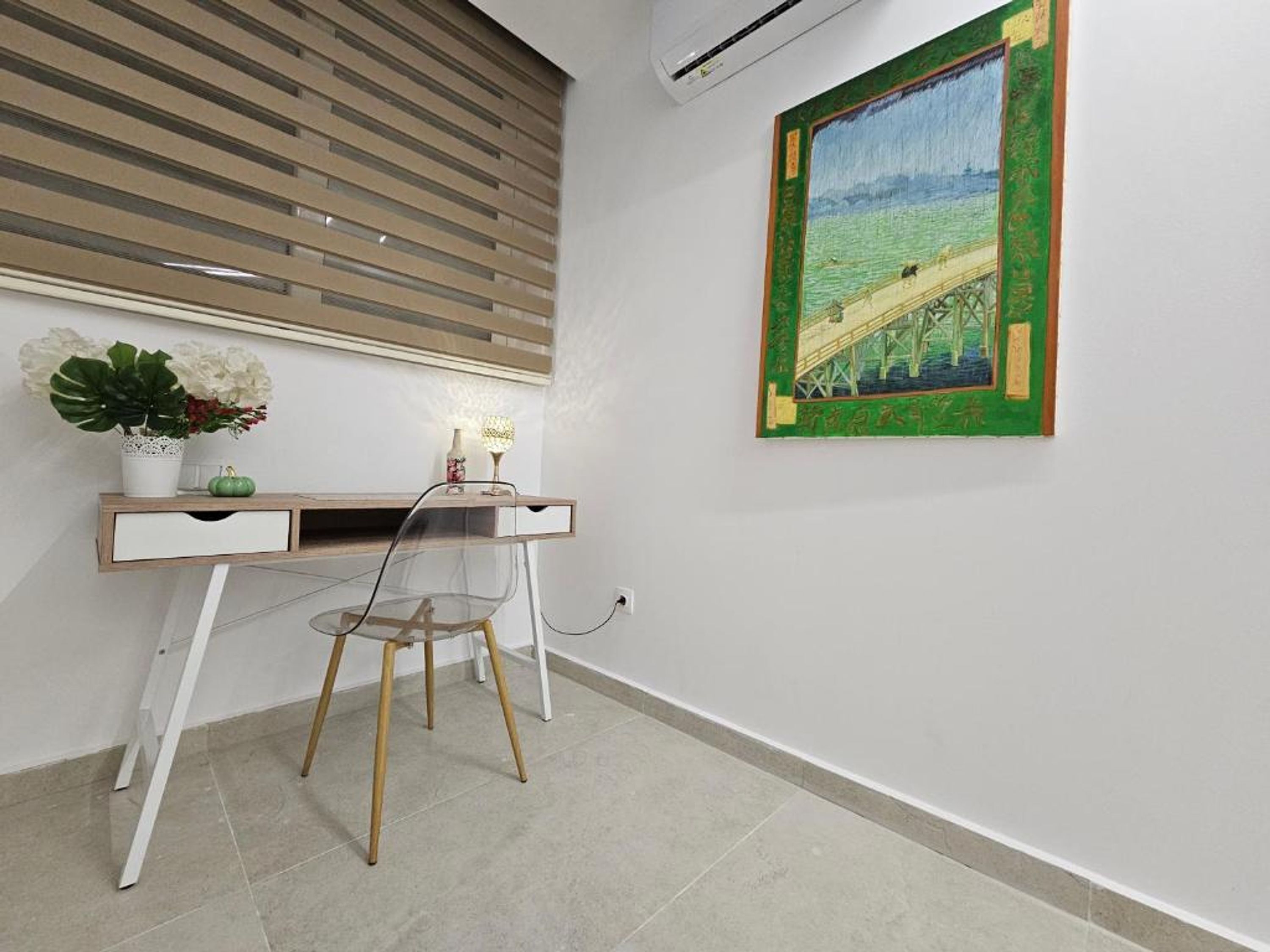 A modern room with a desk, chair, potted plants, and a painting on the wall.