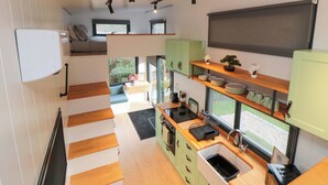 Eine kleine Küche mit Backofen, Spüle und Fenster zum Garten.