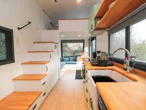 A modern kitchen with wooden countertops, a sink, and a built-in bench. - The Tiny Home (Yarm)