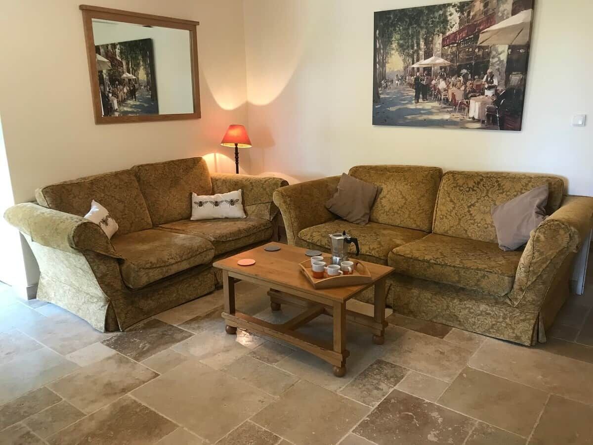 A living room with two sofas, a wooden coffee table, a lamp, and two framed pictures on the wall.