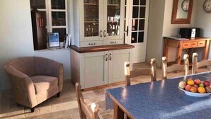 A dining area with a table, chairs, a cabinet with glass doors, and a clock on the wall. - La Maison Tourouzelle (Lauraguel)