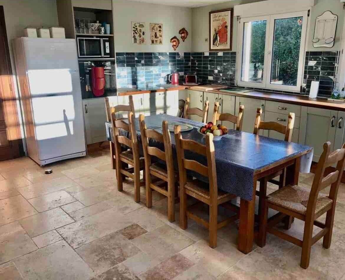 Cuina amb taula de menjador, cadires i nevera.