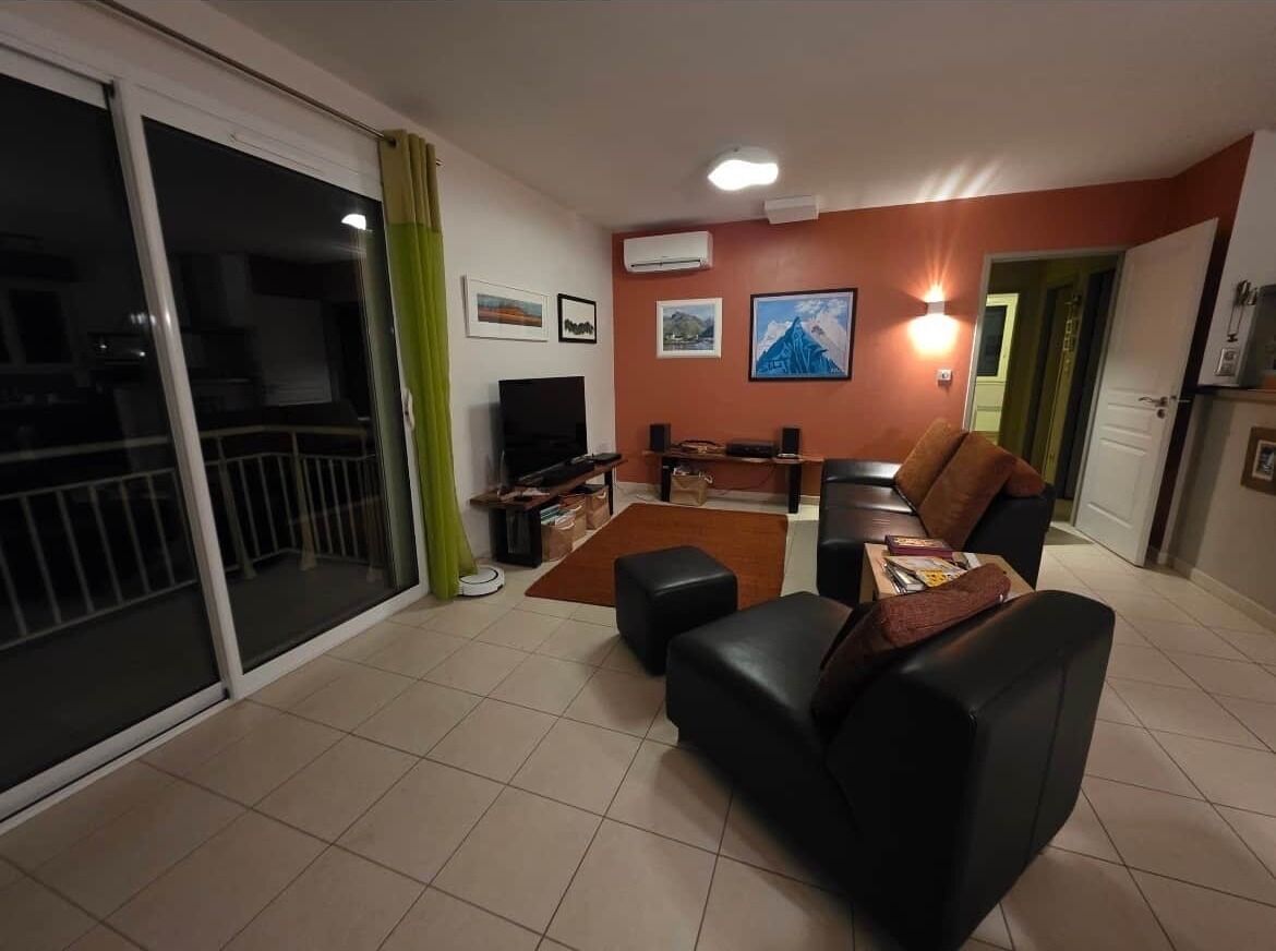 Un salón con sofá, televisor, chimenea y puerta corrediza de vidrio.