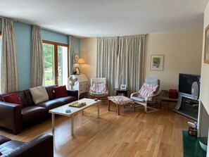 A living room with a sofa, chairs, a coffee table, a TV, and curtains. - La Maison de la lavande (Quillan)