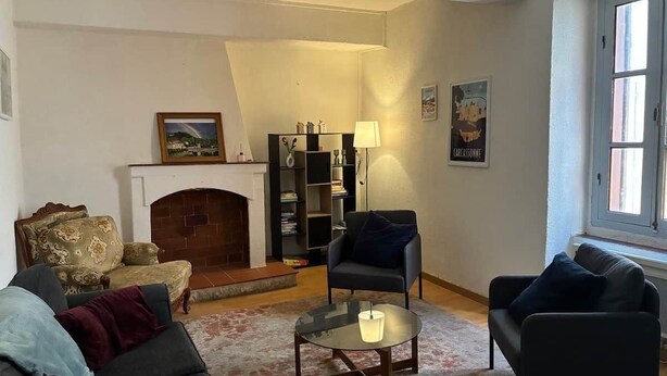 Una sala de estar con chimenea, una estantería y un ventanal.