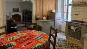 Cocina compacta con comedor, estufa integrada y refrigerador.