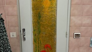 Un baño con puerta blanca, azulejos rosas, un perchero y una toalla.