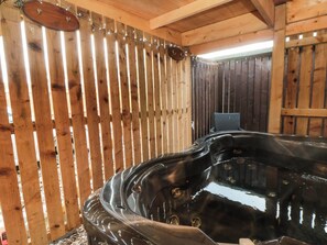 A hot tub in a wooden cabin with a chair and a wooden fence. - Toote Suite (Yarm)