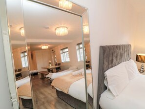 Een hotelkamer met twee bedden, een spiegel, een bureau en een kroonluchter.