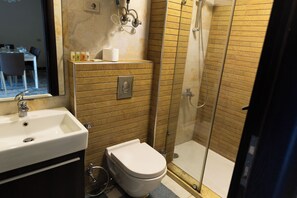 Een badkamer met een wit wastafel, toilet en douchecabine met glazen wanden.