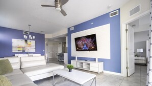 Ein modernes Wohnzimmer mit Sofa, Couchtisch, Fernseher und Deckenventilator.