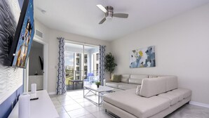 Ein modernes Wohnzimmer mit einer Couch, einem Couchtisch und einem an der Wand befestigten Fernseher.