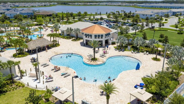 Ein Resort mit großem zentralem Pool, mehreren Gebäuden und einem See im Hintergrund.