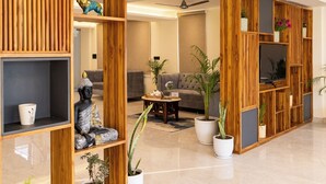 Una sala de estar moderna con un separador de madera, una estatua de Buda y plantas en macetas.