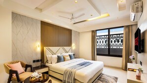 Una habitación de hotel moderna con cama, zona de estar y vistas al balcón.