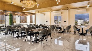 Un comedor amplio con techos altos, candelabros y grandes ventanales que ofrecen vistas de la ciudad.