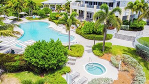 Ein Resort mit großem Schwimmbad, Liegebereichen und einem mehrstöckigen Gebäude.