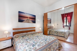 Une chambre à coucher avec un lit, une table de chevet, un miroir et un tableau accroché au mur.