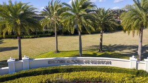 Une enseigne indiquant l’emplacement du complexe Encore Resort, visible lors d’une réunion, entourée de palmiers et de pelouses bien entretenues.