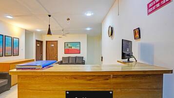 A reception desk with a sign reading 'Collection,' a ceiling fan, framed artwork on the walls, and a television on a stand.