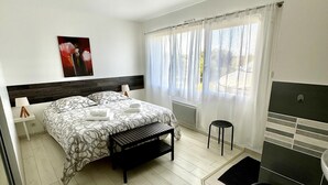 A bedroom with a bed, bedside table, lamp, and a window with curtains. - Neiz Vran House Facing the Sea (Kerlouan)