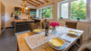 A modern kitchen with built-in appliances, a dining area with a table set for two, and large windows offering a view of greenery. - Mediterranean vacation home with swimming pool in a quiet location (Krizisce)