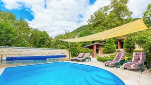 A swimming pool with lounge chairs and a shaded area. - Mediterranean vacation home with swimming pool in a quiet location (Krizisce)