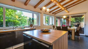 A modern kitchen with a central island, large windows, and a dining area with a brick wall and outdoor view. - Mediterranean vacation home with swimming pool in a quiet location (Krizisce)