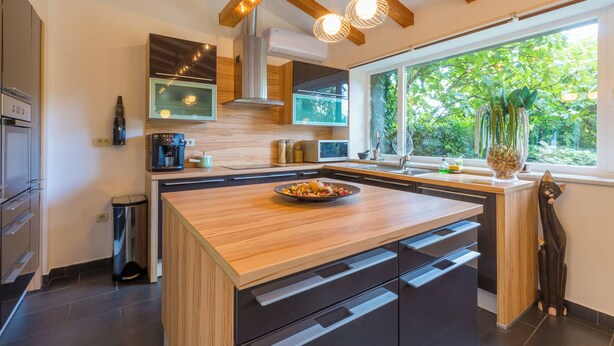 A modern kitchen with a central island, built-in appliances, and a large window providing a view of greenery. - Mediterranean vacation home with swimming pool in a quiet location (Krizisce)