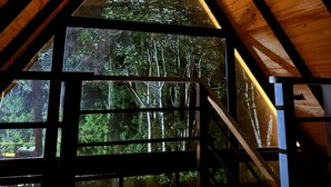 A triangular wooden ceiling structure with a large window providing a view of a forested area. - Alpine Villa | Mountain| Fire pit| Heated Jacuzzi (Jarabacoa)