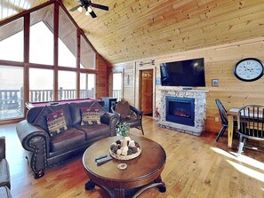 A cozy living room with a fireplace, a large TV, and a comfortable sofa. - Smoky Mountain View | Great Views, Hot Tub, Game Tables (Sevierville)