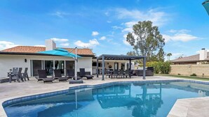 A swimming pool with lounge chairs and a covered patio area. - Entertaining Estate: Pickleball, B-ball & Golf! (Phoenix)
