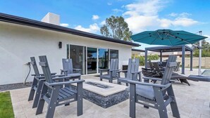 An outdoor patio with a fire pit, chairs, and a covered seating area. - Entertaining Estate: Pickleball, B-ball & Golf! (Phoenix)