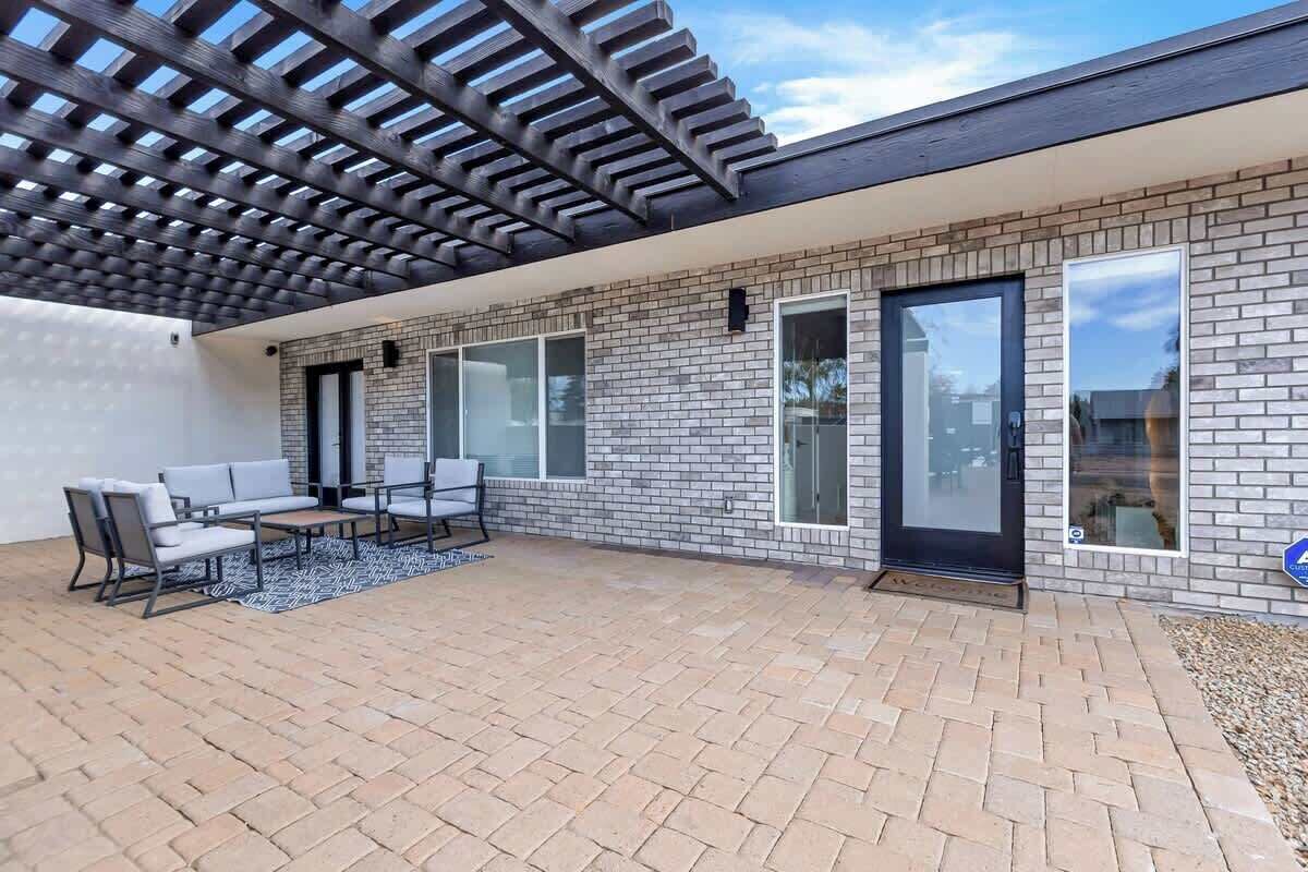 A covered patio area with a brick floor, a seating arrangement, and a pergola structure.