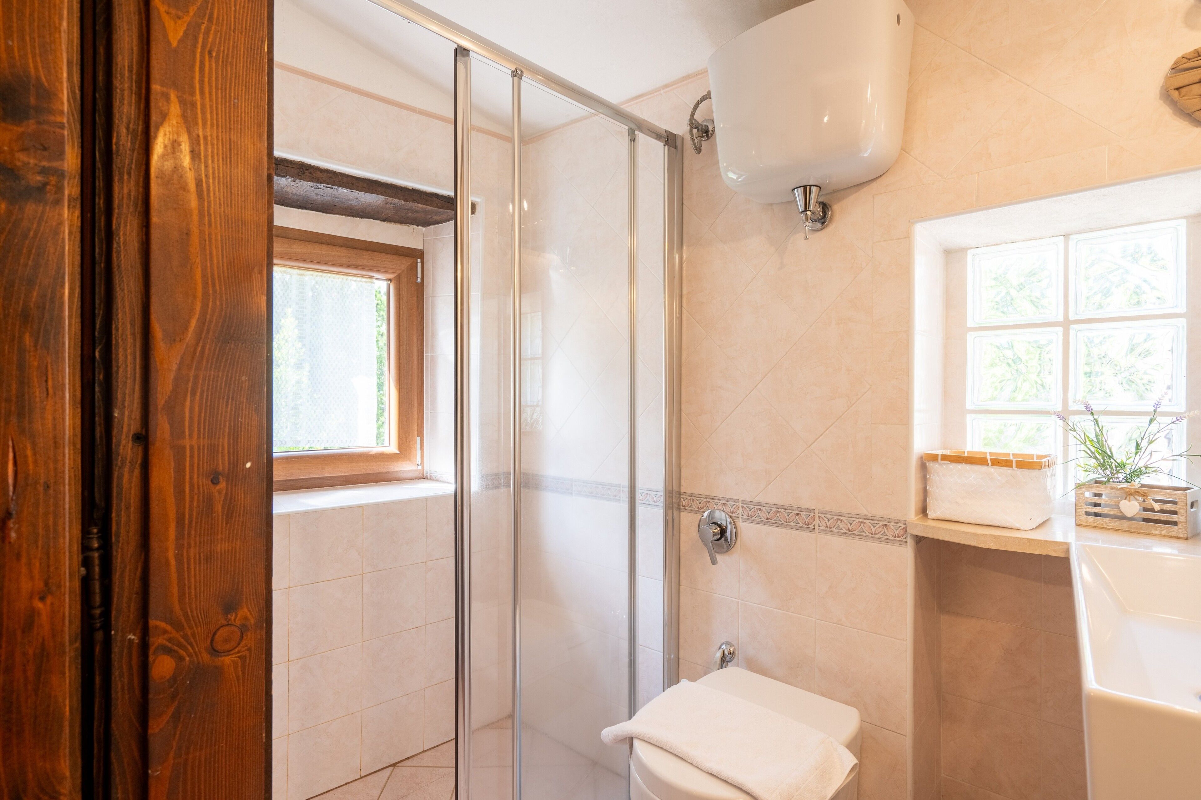 Une salle de bain avec une douche à parois de verre, des toilettes, un lavabo et une fenêtre.
