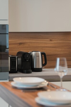 A modern kitchen with a coffee maker, toaster, and a wine glass on the counter. - Modern City Center Apartment at Mirabell Palace (Salzburg Stadt)
