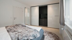 A modern bedroom with a bed, a large mirror, a wardrobe, and a television. - Modern City Center Apartment at Mirabell Palace (Salzburg Stadt)