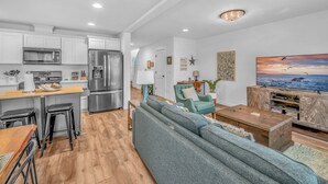 Una cucina moderna con mobili bianchi, elettrodomestici in acciaio inossidabile e un'area pranzo in legno.