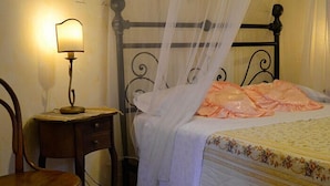 A bedroom with a bed, a nightstand, a chair, and a lamp.