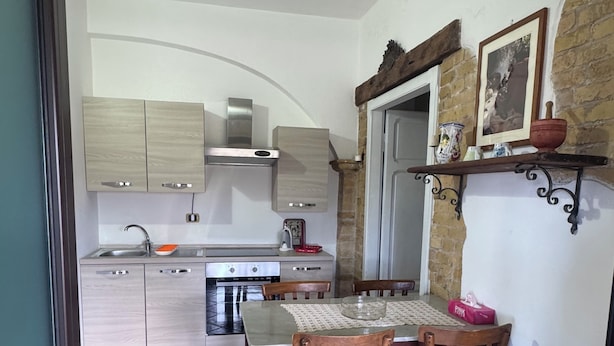 A kitchen with wooden cabinets, a stainless steel range, and a dining table with chairs.
