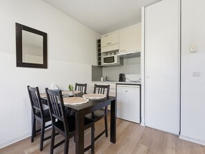 A compact kitchen with a dining table, chairs, a microwave, and a refrigerator. - Charming apartment for 4 people with a balcony (Grasse)