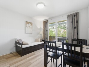 A room with a bed, a dining table with chairs, a lamp, and a view through a window. - Charming apartment for 4 people with a balcony (Grasse)