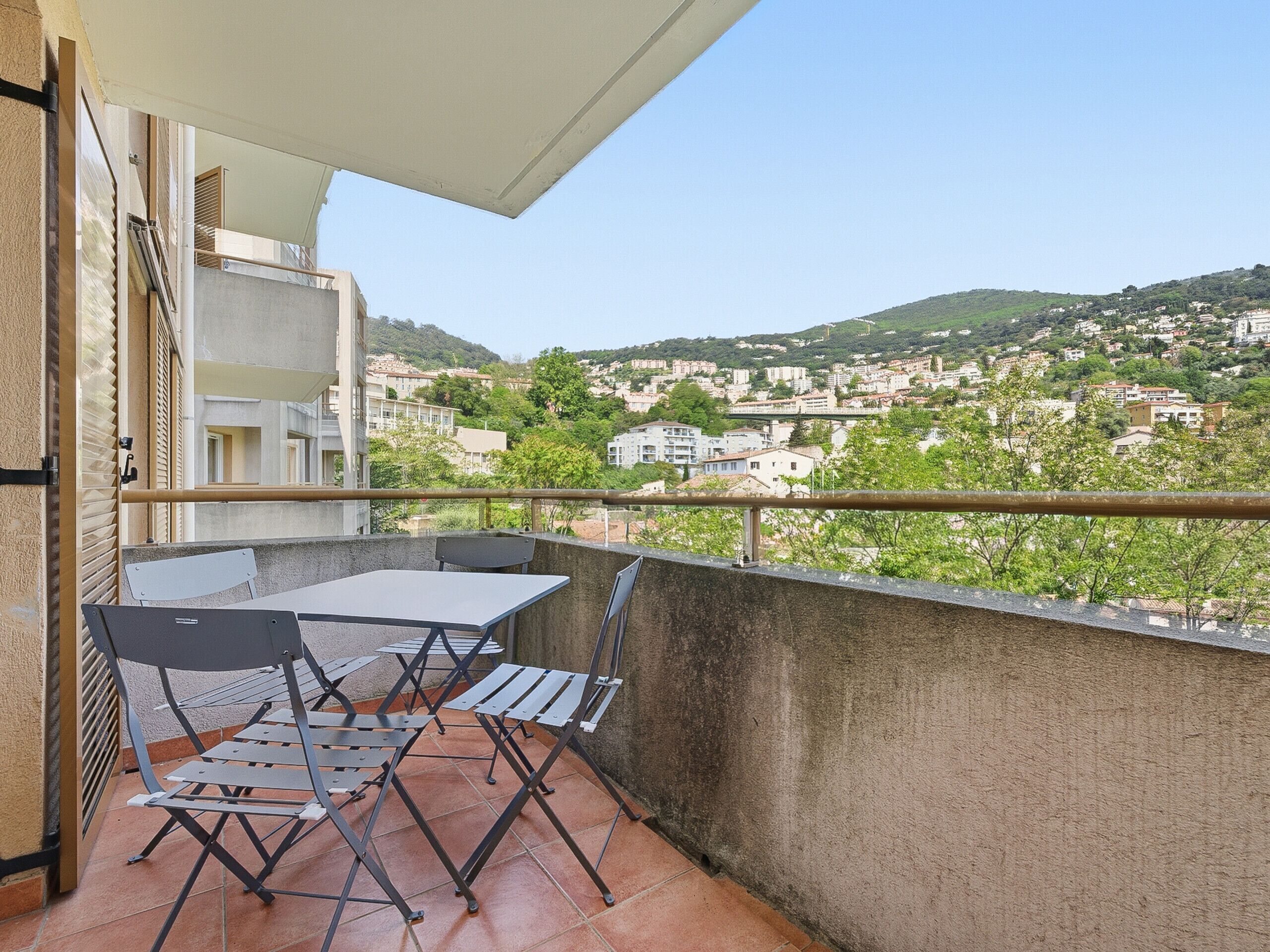Ein Balkon mit Tisch und Stühlen mit Blick auf eine Hügelstadt.