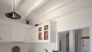 A kitchen with white cabinets, a built-in oven, a hanging light fixture, and a mirror above the counter. - Casa Vento - Maisonette near Santa Maria beach (SANTA MARIA)