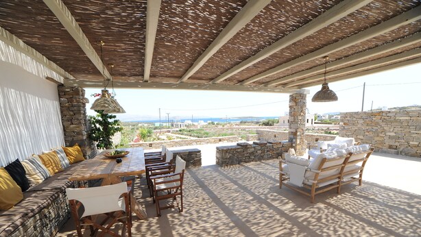 An outdoor patio with stone walls, a wooden table, and chairs. - Casa Vento - Maisonette near Santa Maria beach (SANTA MARIA)
